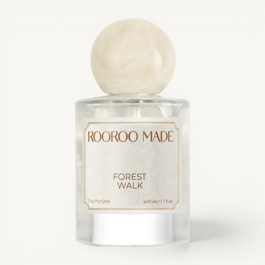 A clear glass bottle of Rooroo Made 'Forest Walk' dog perfume with a round, polished cream-colored stone cap, set against a clean white background.